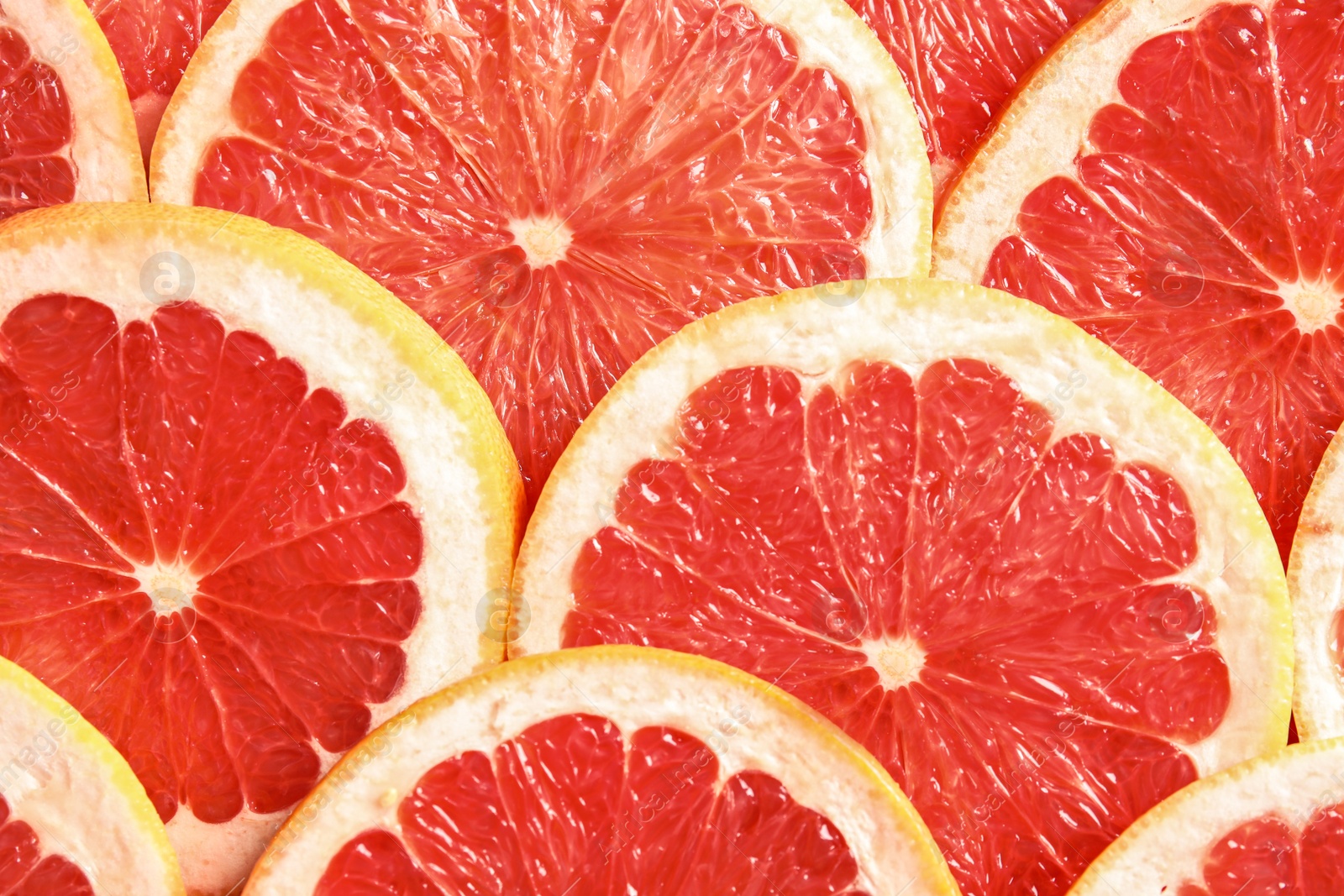 Photo of Many sliced fresh grapefruits as background, top view