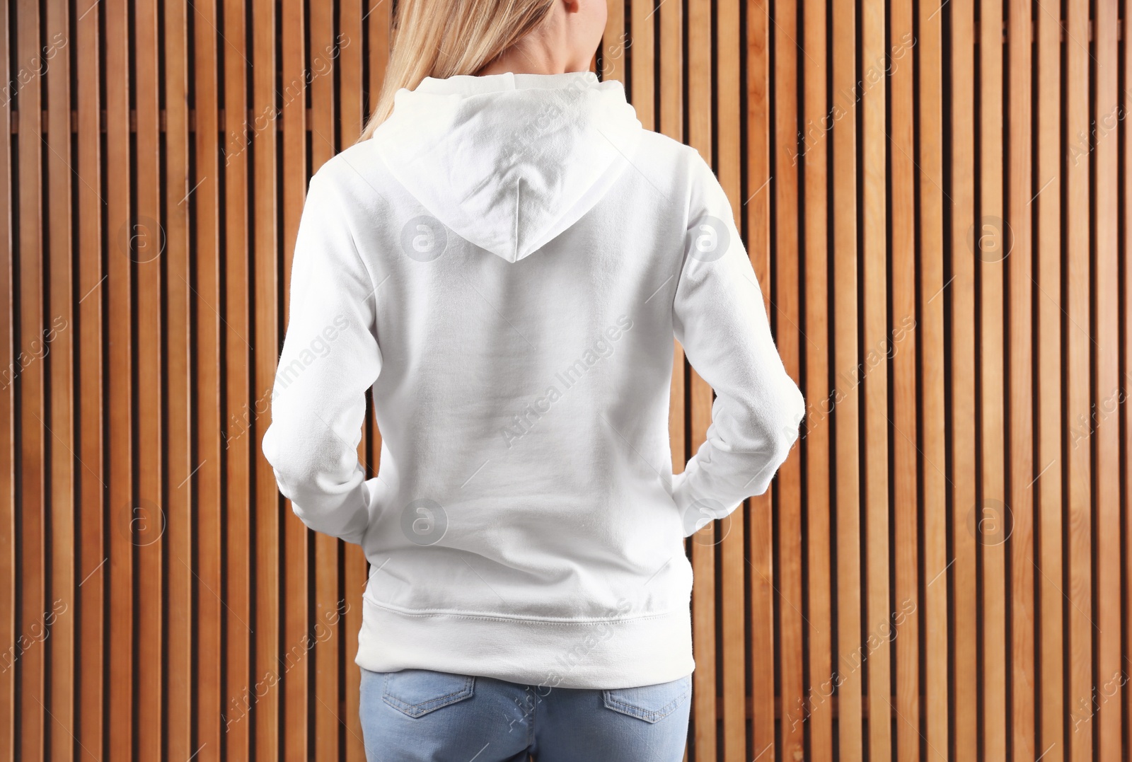 Photo of Woman in hoodie sweater on wooden background. Space for design