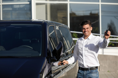 Photo of Man with key near car on city street. Buying new auto