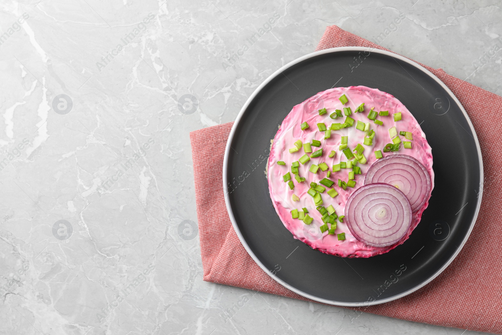 Photo of Herring under fur coat salad on light grey table, top view with space for text. Traditional Russian dish