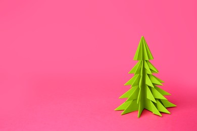 Photo of Origami art. Handmade paper Christmas tree on pink background, space for text