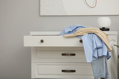 Photo of Set of clothes on white chest of drawers indoors