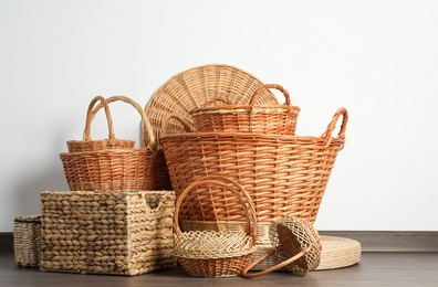 Photo of Many different wicker baskets made of natural material on floor near light wall