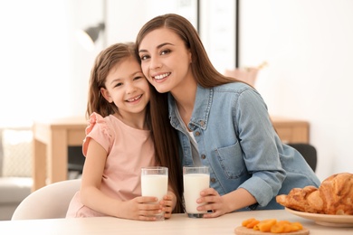 Mother and daughter having breakfast with milk at table