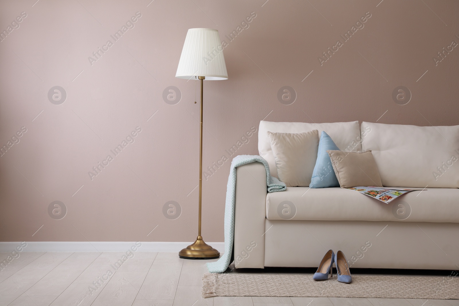 Photo of Stylish room living interior with comfortable sofa and lamp near beige wall