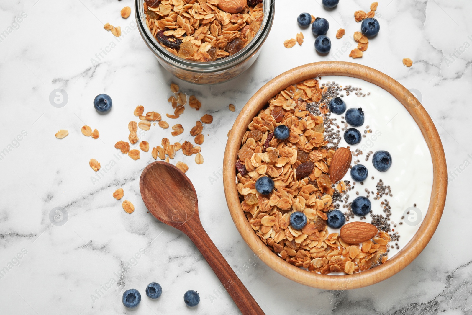 Photo of Tasty homemade granola served on white marble table, flat lay. Healthy breakfast