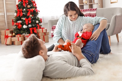 Happy couple with baby celebrating Christmas together at home