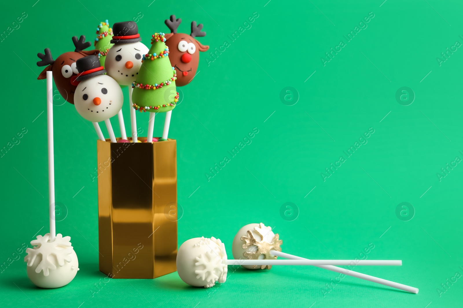 Photo of Delicious Christmas themed cake pops on green background