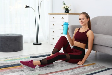 Woman with bottle of protein shake in living room