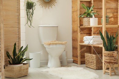 Photo of Toilet bowl and green houseplants in bathroom. Interior design