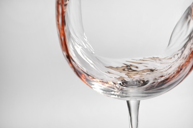Photo of Pouring rose wine into glass on light background, closeup