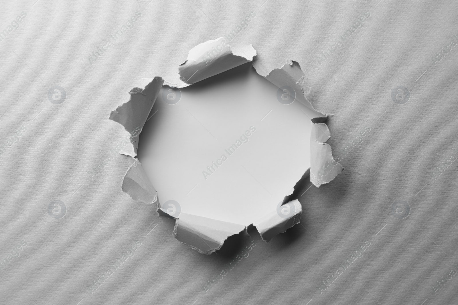 Photo of Hole in white paper on light background