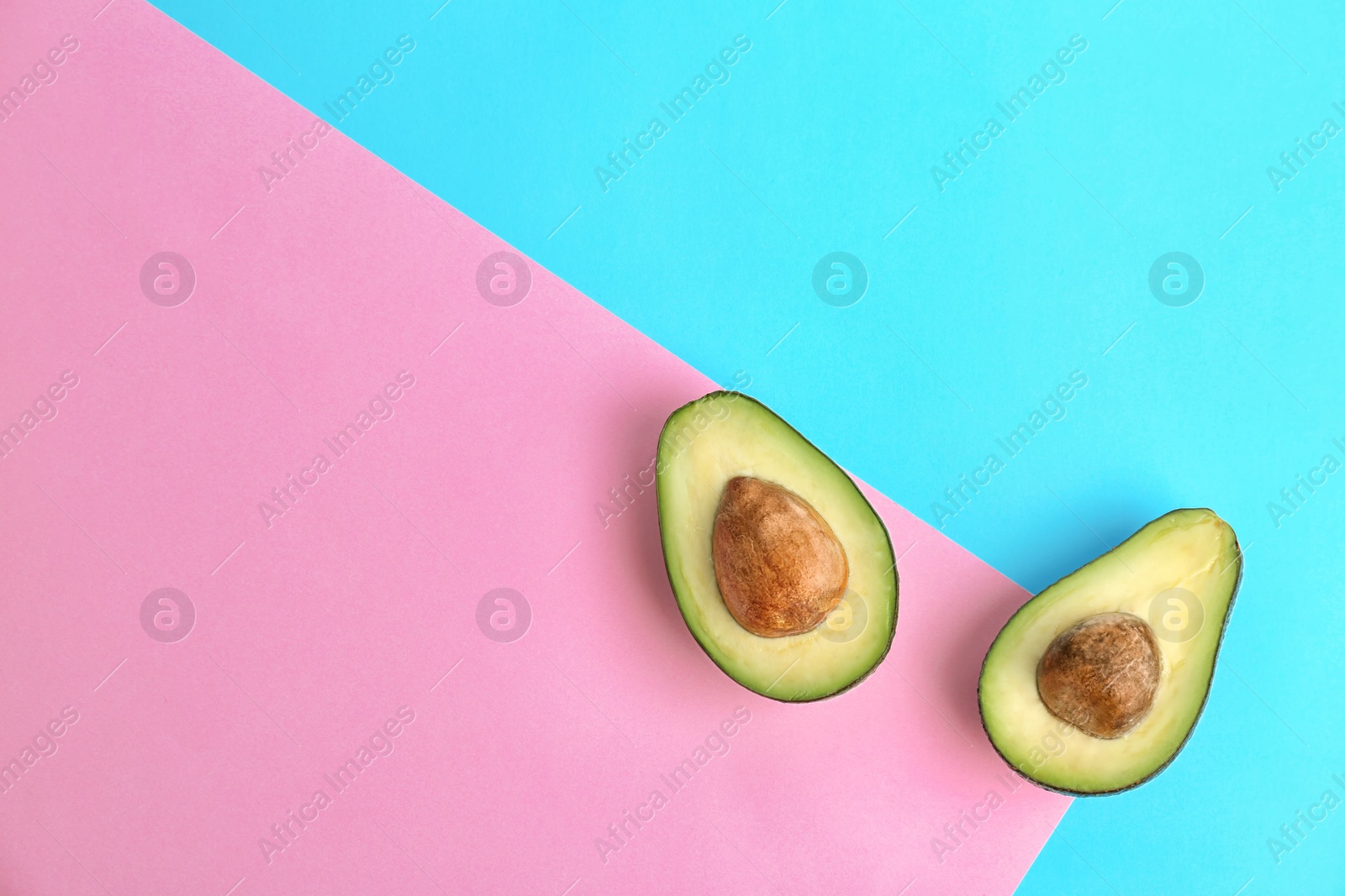 Photo of Halves of ripe avocados on color background, top view