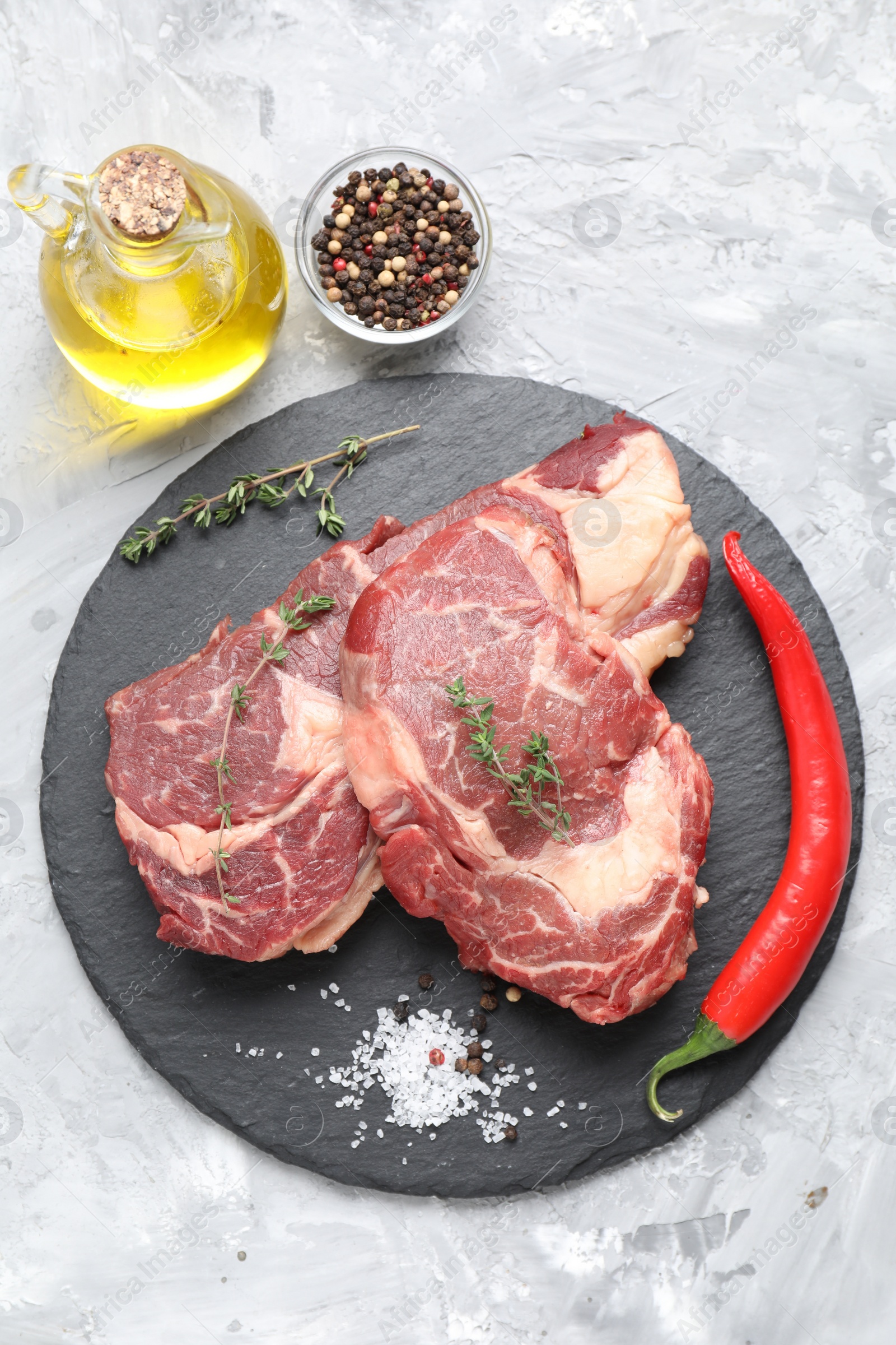 Photo of Fresh raw beef cut with different spices on light grey textured table, flat lay