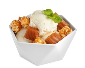 Photo of Bowl of delicious ice cream with caramel candies, popcorn and mint on white background