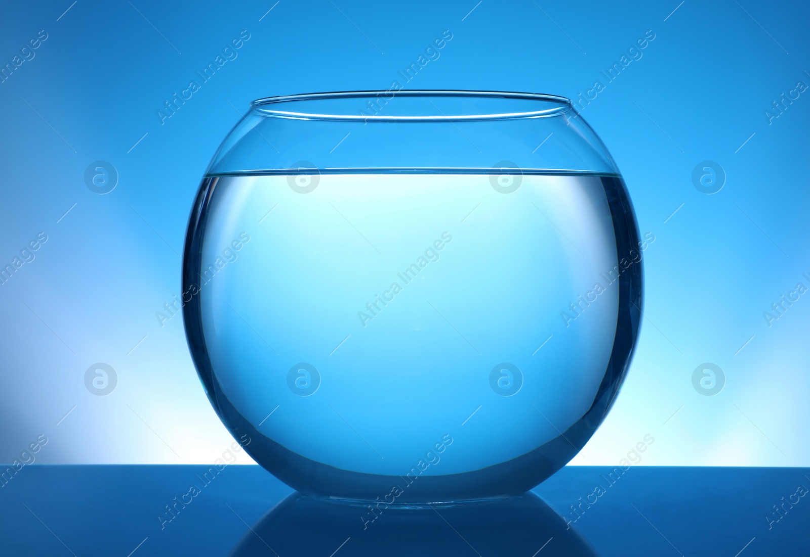 Photo of Glass fish bowl with clear water on blue background