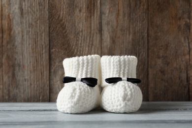 Photo of Handmade baby booties on table against wooden background