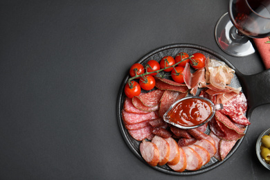 Different types of sausages with sauce served on black background, flat lay. Space for text