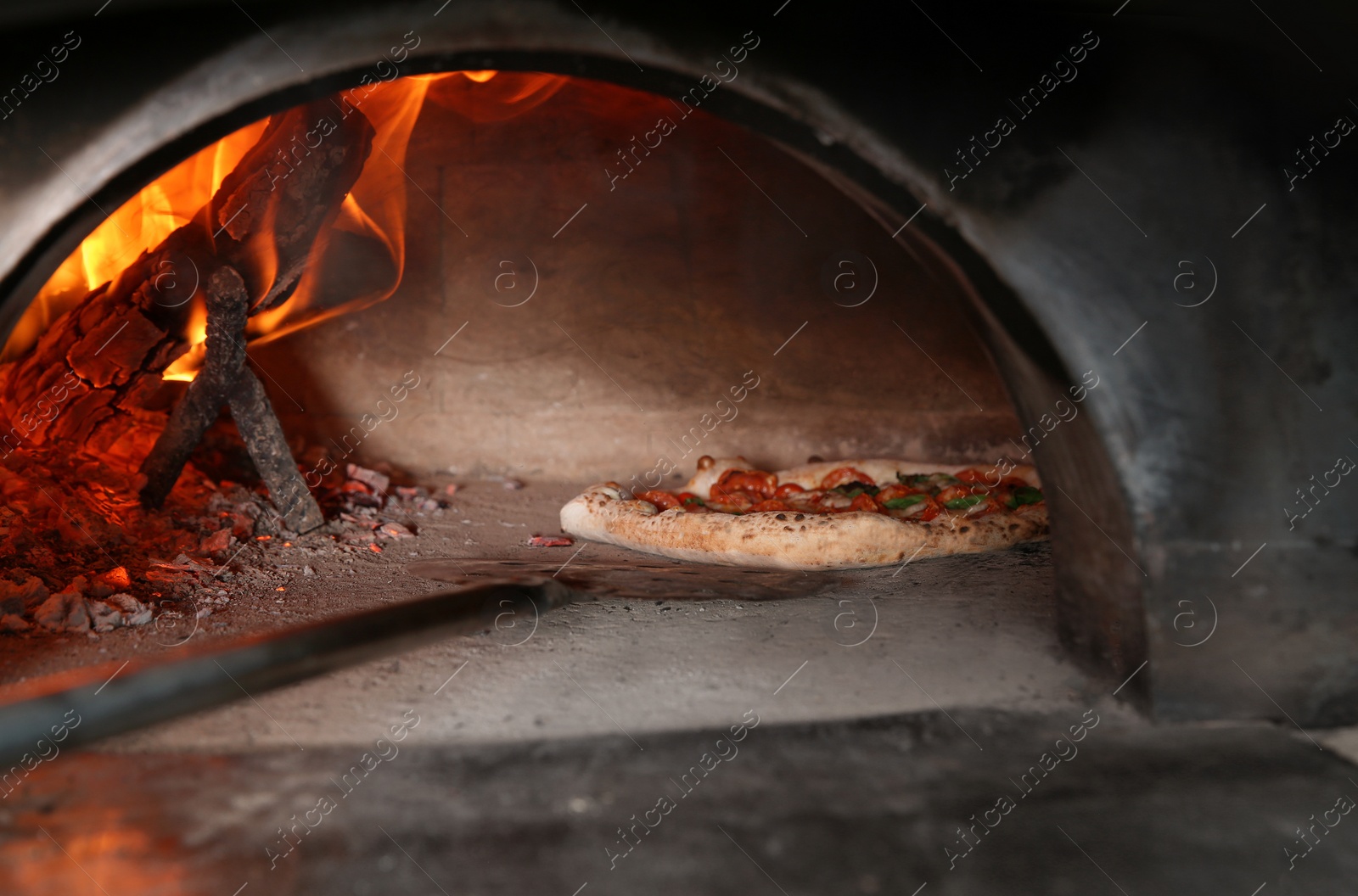 Photo of Taking out tasty pizza from oven in restaurant kitchen