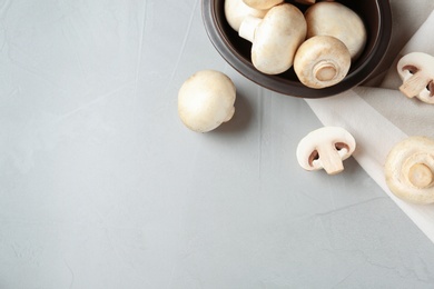 Photo of Fresh champignon mushrooms and plate on table, top view. Space for text