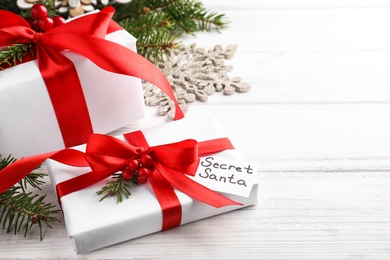 Photo of Presents from secret Santa and Christmas decor on white wooden table, space for text