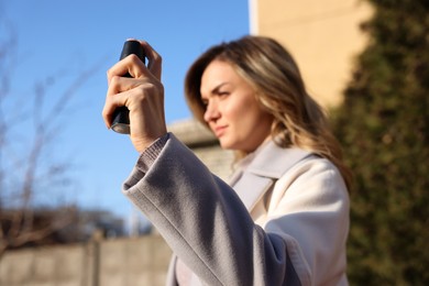 Photo of Young woman using pepper spray outdoors, focus on hand