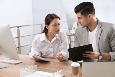 Businessman helping intern with work in office