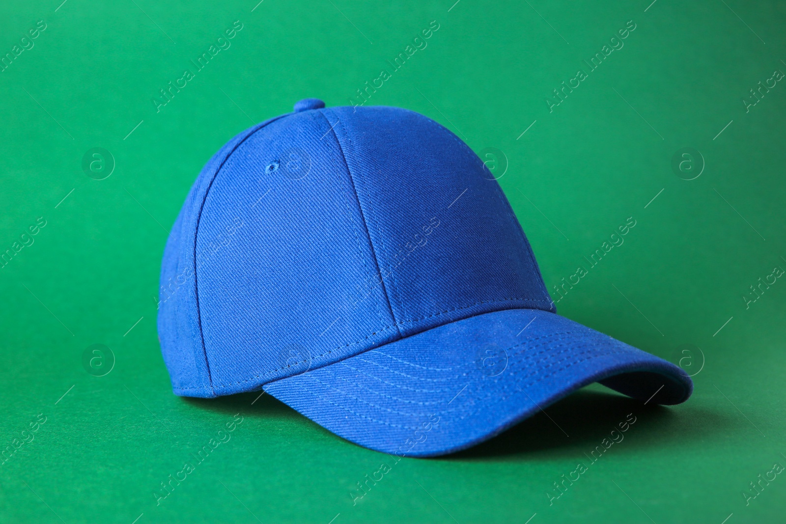 Photo of Stylish blue baseball cap on green background