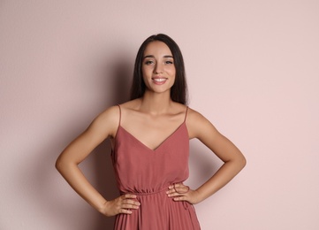 Photo of Young woman wearing stylish dress on pale pink background