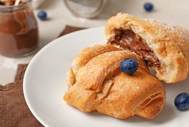 Photo of Tasty croissant with chocolate on plate, closeup