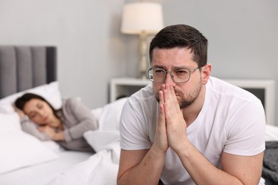 Photo of Stressed husband after quarrel with his wife in bedroom, selective focus. Relationship problems