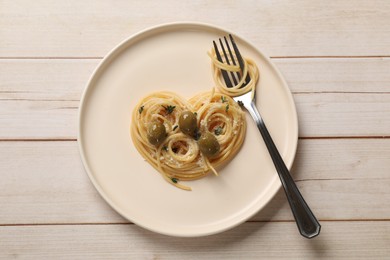 Photo of Heart made of tasty spaghetti, fork, olives and cheese on light wooden table, top view