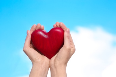 Photo of Woman holding decorative heart in hands on color background, space for text