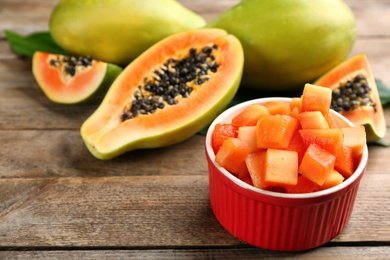 Dices of fresh ripe papaya in bowl on wooden table