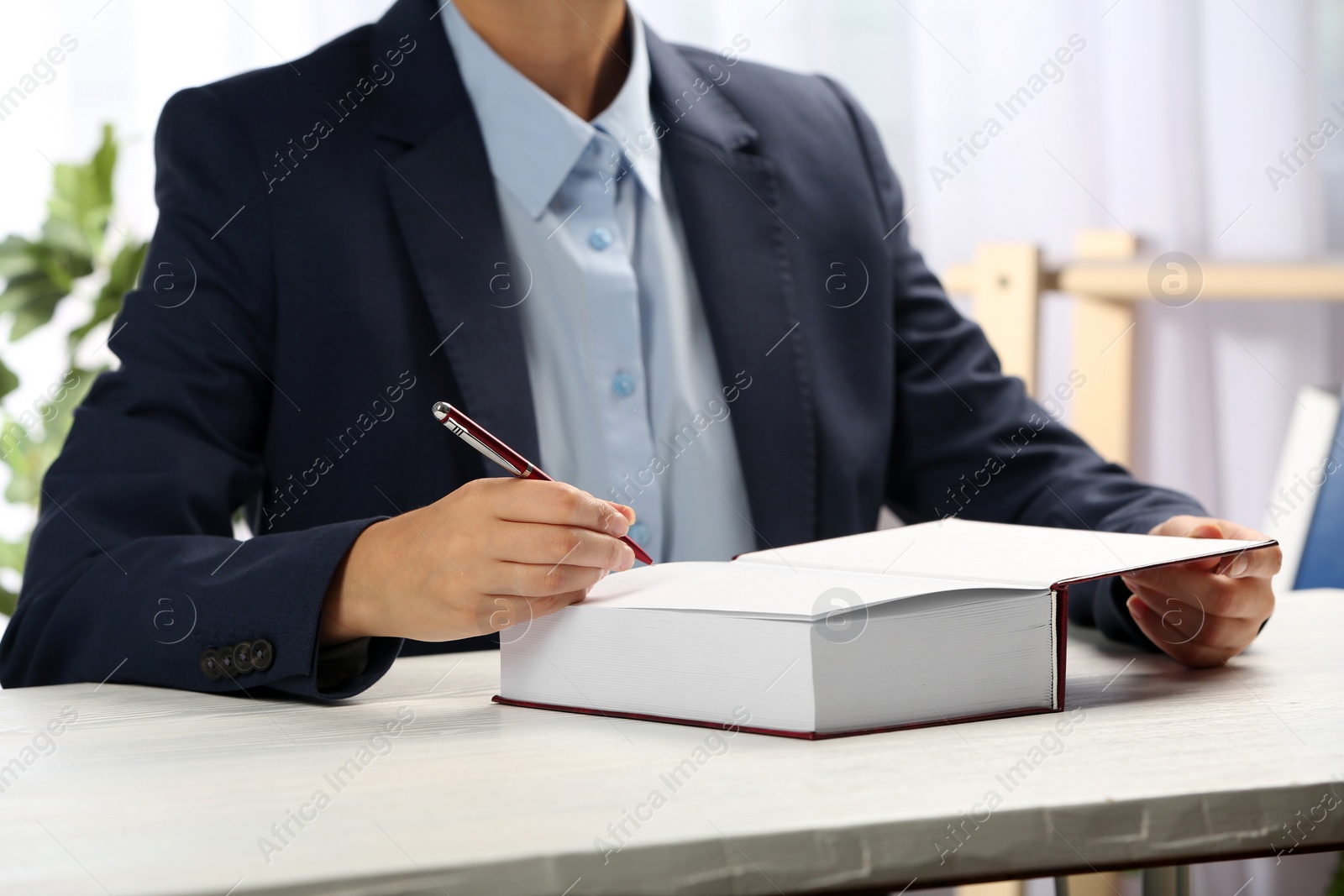 Photo of Writer signing autograph in book at table, closeup