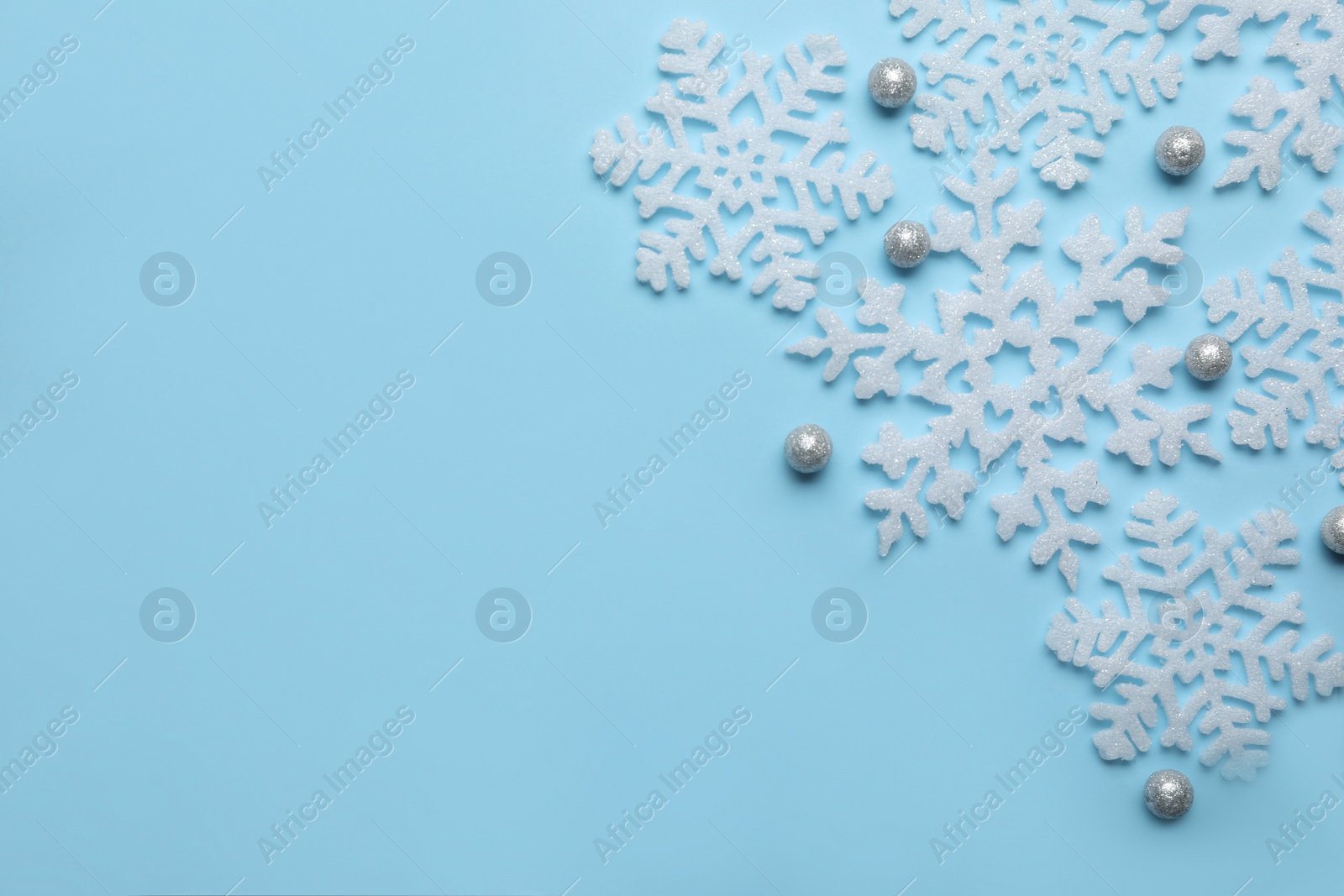 Photo of Beautiful decorative snowflakes on light blue background, flat lay. Space for text