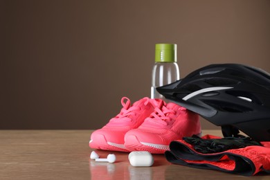 Photo of Different cycling accessories on wooden table against brown background, space for text