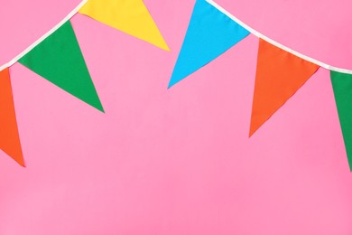 Bunting with colorful triangular flags on pink background. Space for text