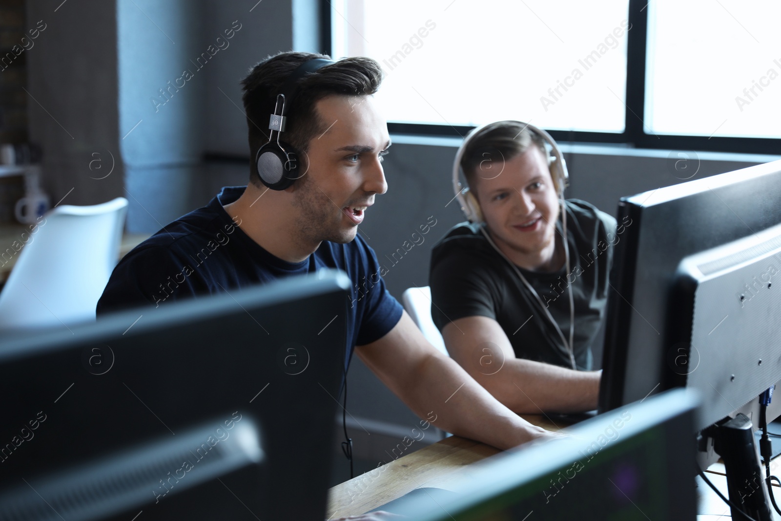 Photo of Men playing video games in internet cafe