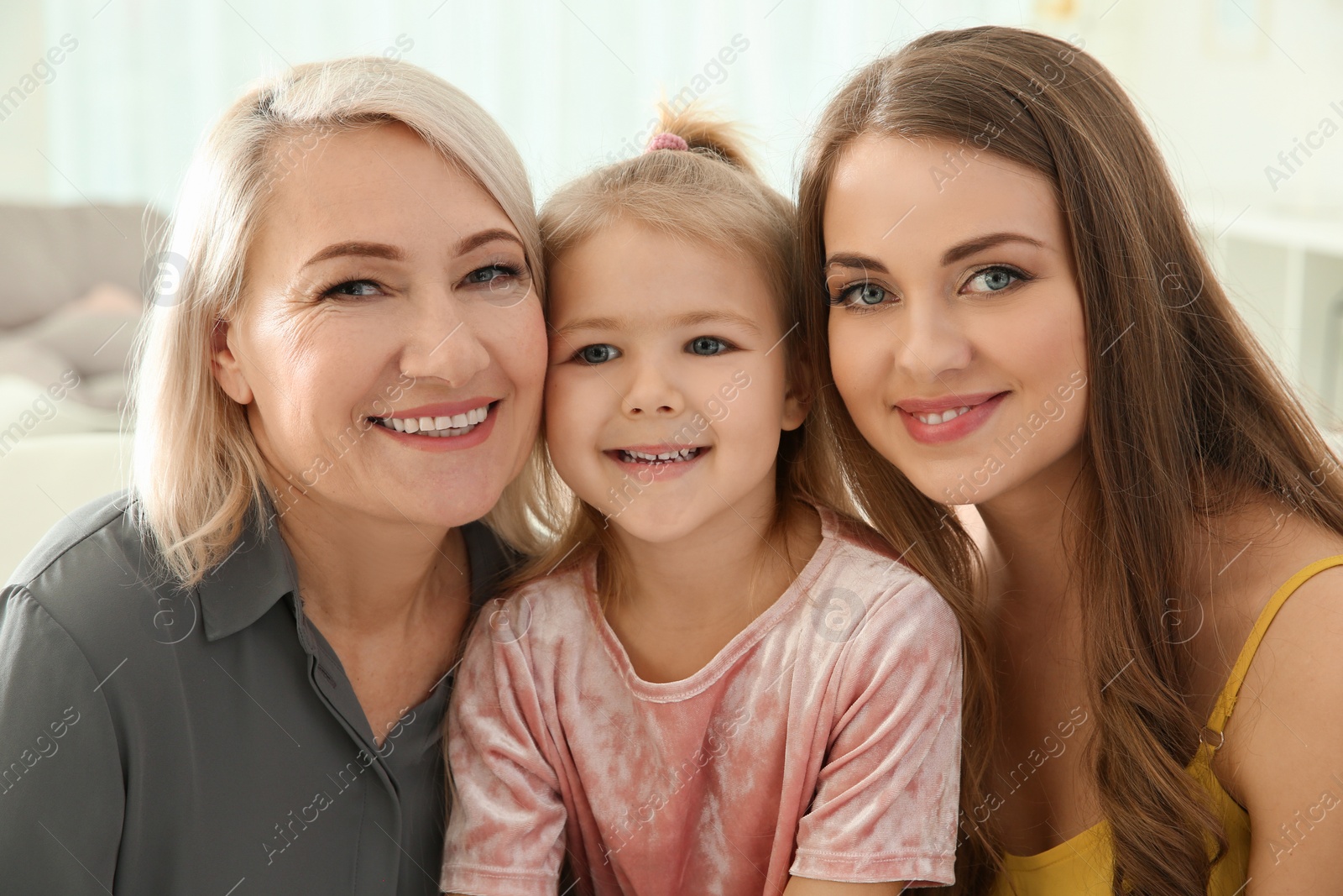 Photo of Happy young woman with her mother and daughter at home