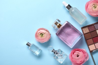 Flat lay composition with different makeup products and beautiful spring flowers on light blue background, space for text