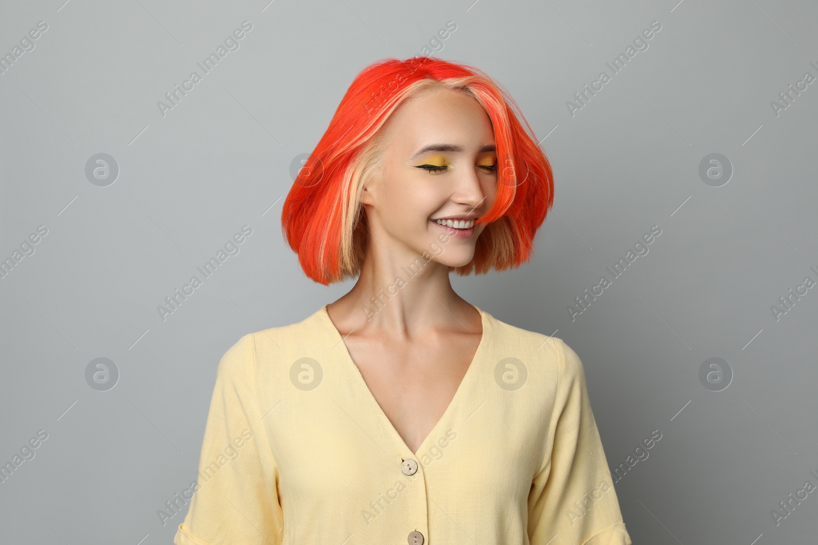 Photo of Beautiful young woman with bright dyed hair shaking head on light grey background