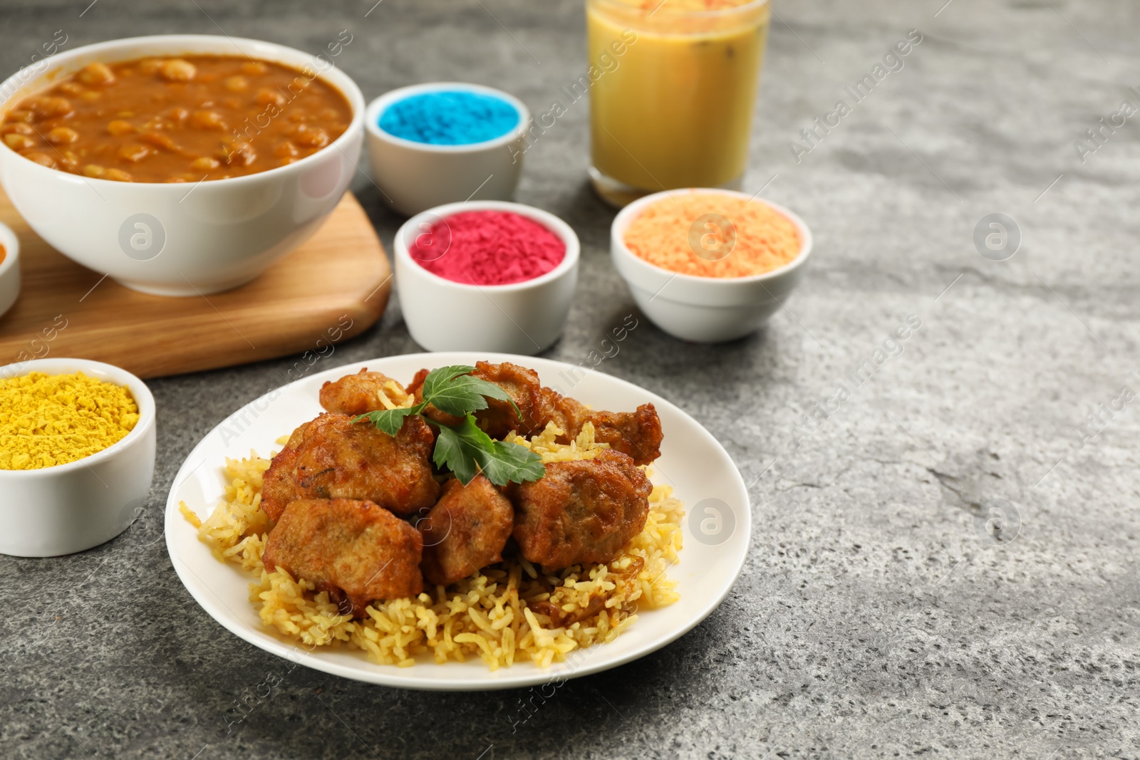 Photo of Traditional Indian food and color powders on grey table. Holi festival celebration