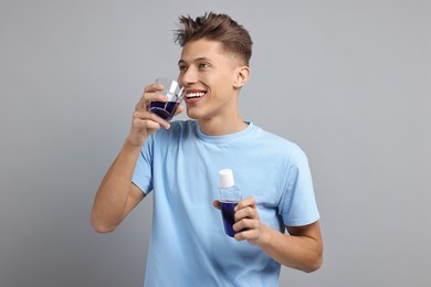 Photo of Young man using mouthwash on light grey background