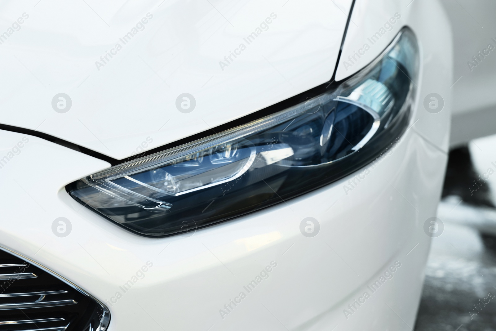 Photo of Luxury white car outdoors, closeup of headlight