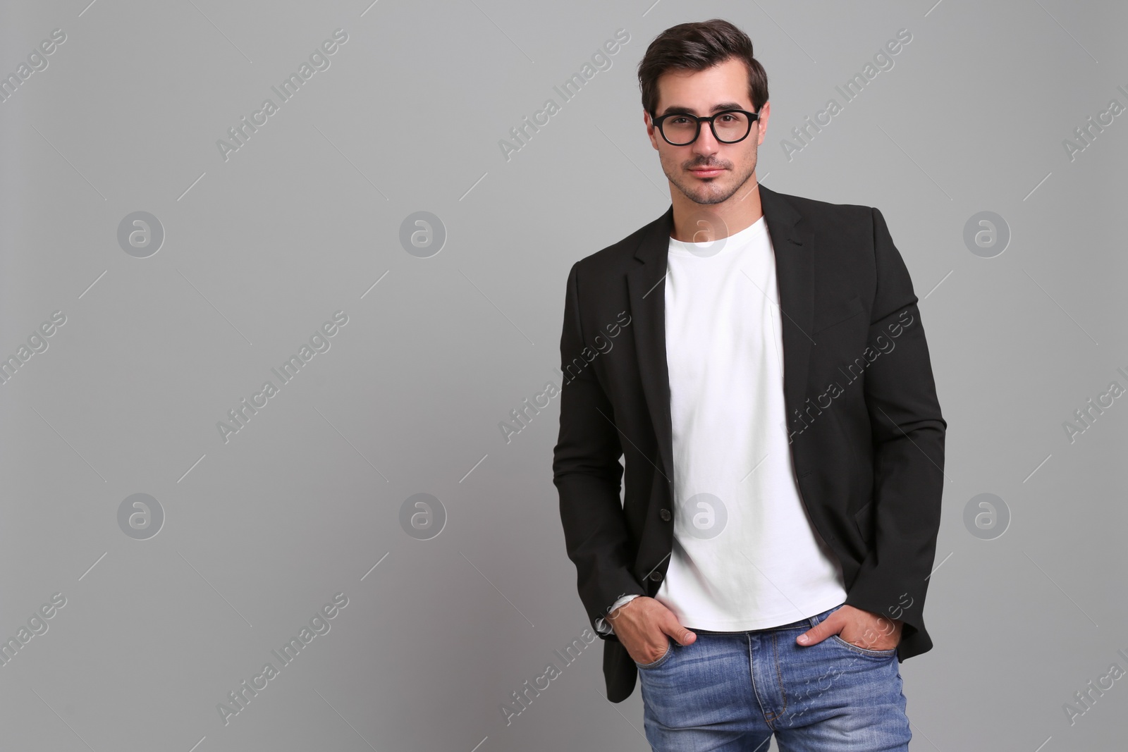 Photo of Handsome young man in casual clothes on grey background. Space for text