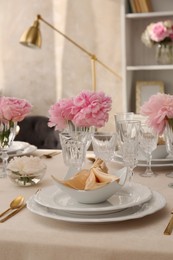 Stylish table setting with beautiful peonies and fabric napkin indoors