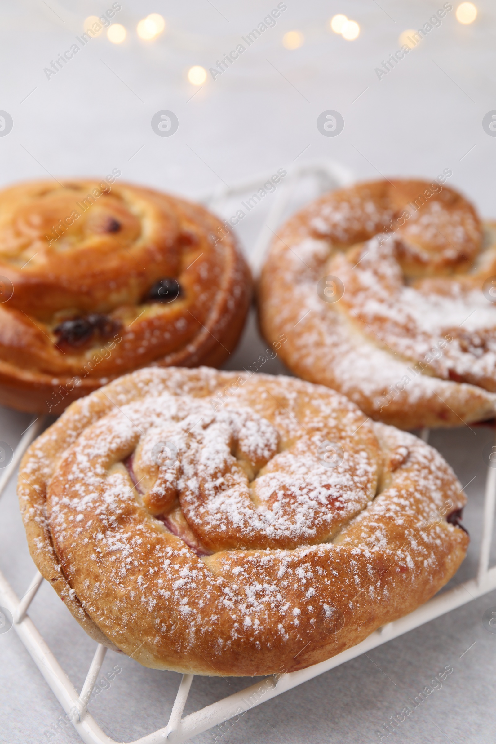 Photo of Delicious rolls with raisins and sugar powder on light table, closeup. Sweet buns