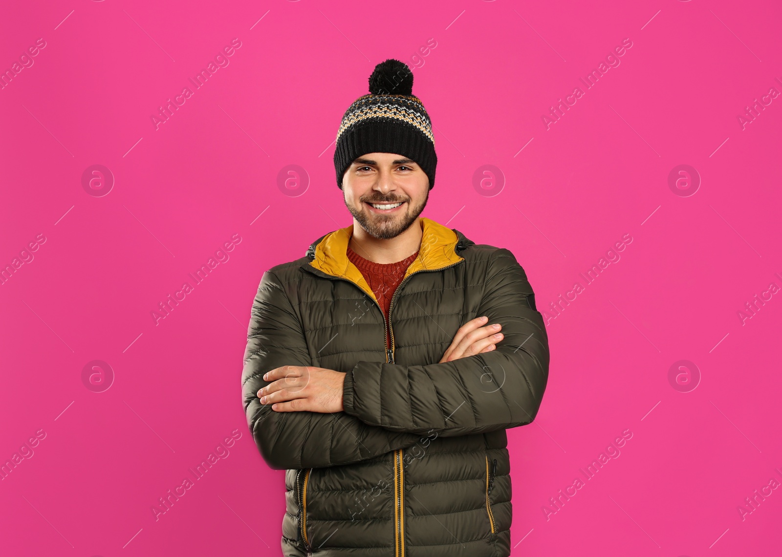 Photo of Happy young man in warm clothes on pink background. Winter vacation