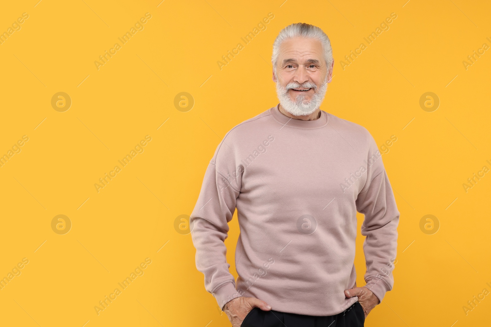 Photo of Portrait of handsome senior man on orange background. Space for text